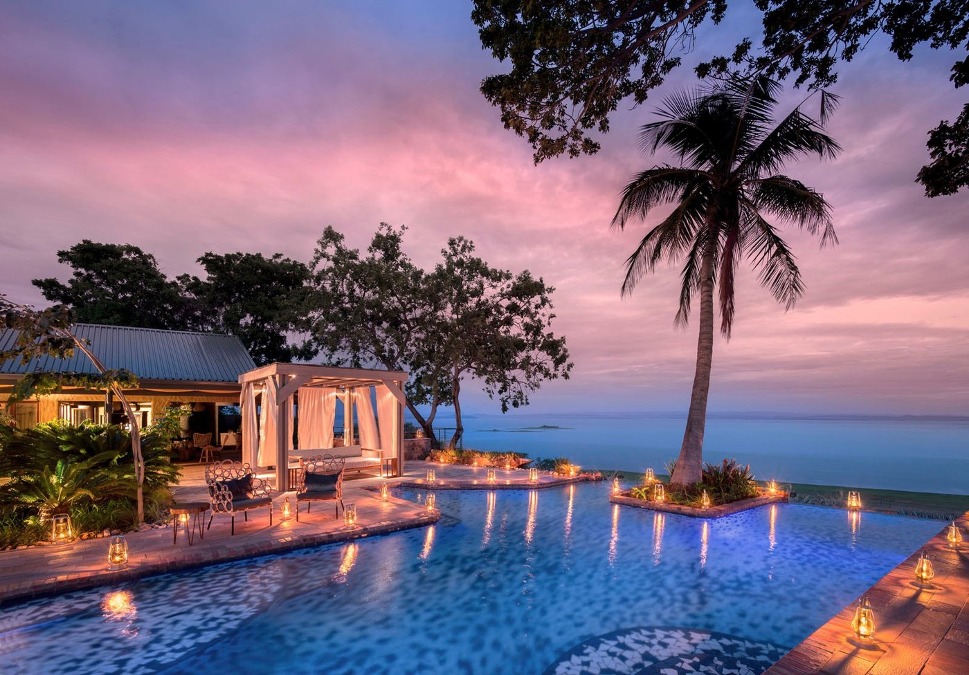 Infinity pool at sunset with palm trees overlooking Lake Kariba at Bumi Hills, Matusadona.