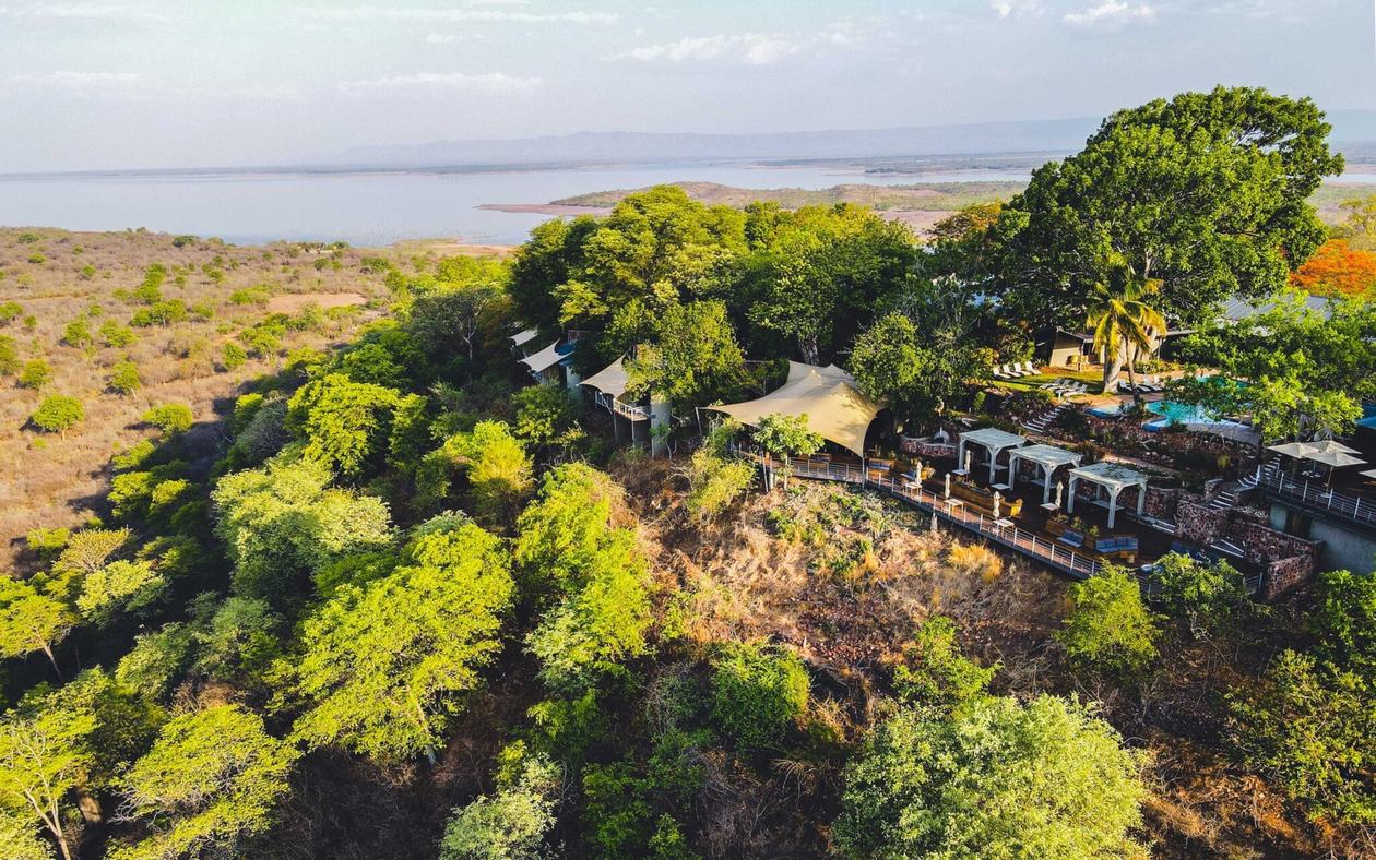 Aerial view of Bumi Hills Safari Lodge's suites set among forest above the lake.