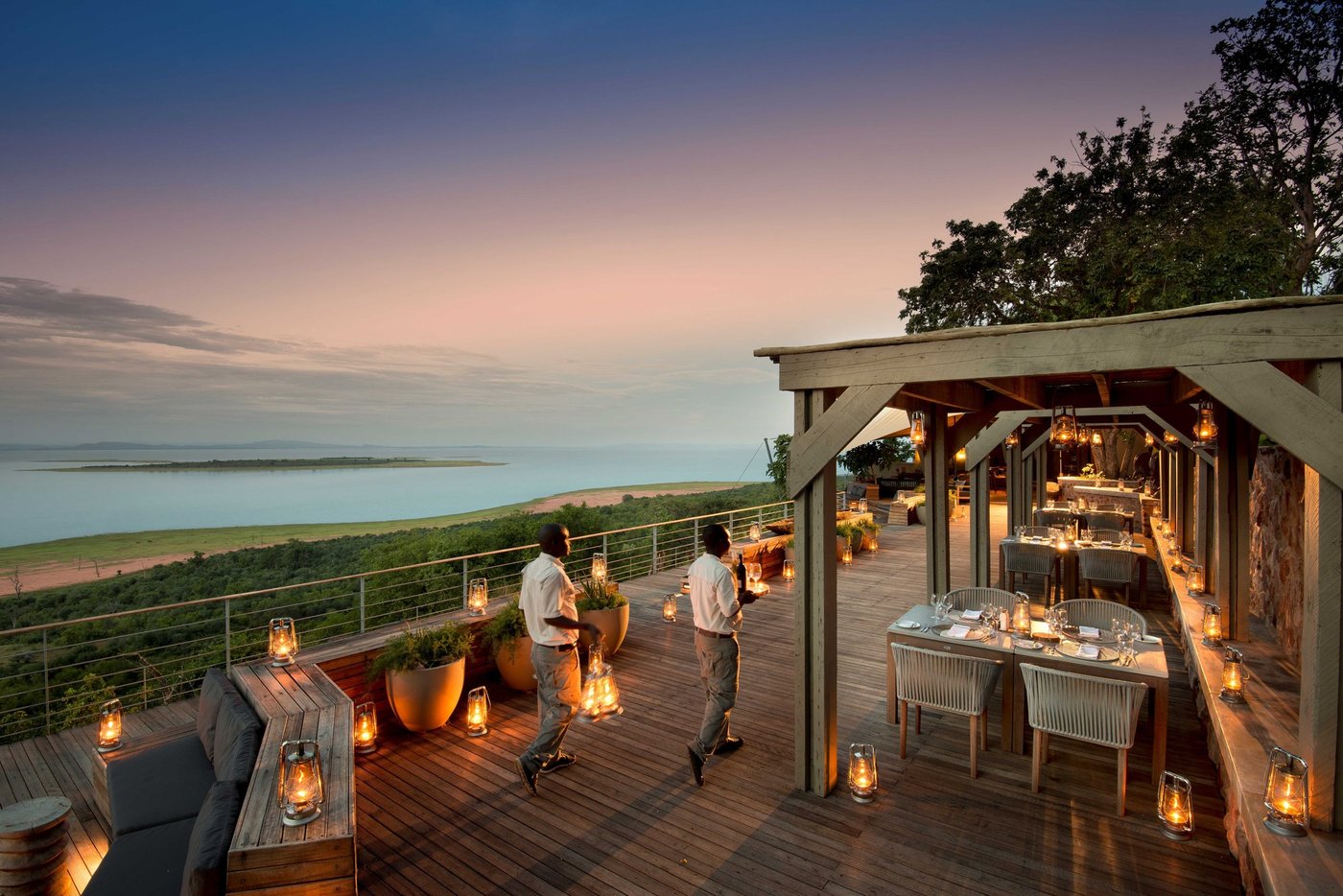 Lantern-lit dining deck overlooking the lake at dusk at Bumi Hills Safari Lodge.