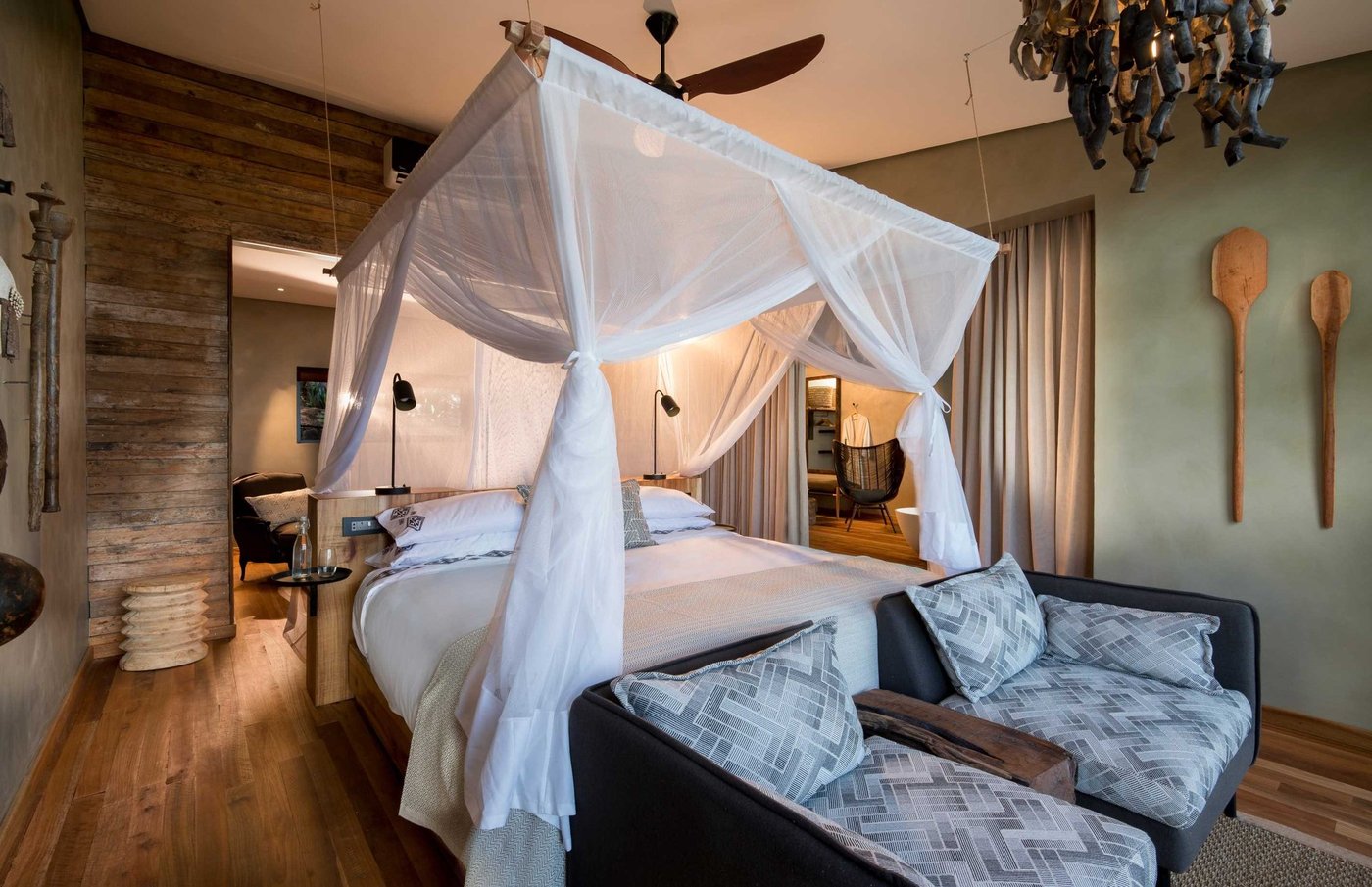 Four-poster canopy bed and lounge seating in a suite at Bumi Hills Safari Lodge.