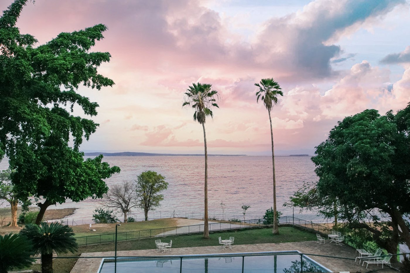 Sunset over Lake Kariba with palm trees and the pool at Cutty Sark Lodge, Matusadona.