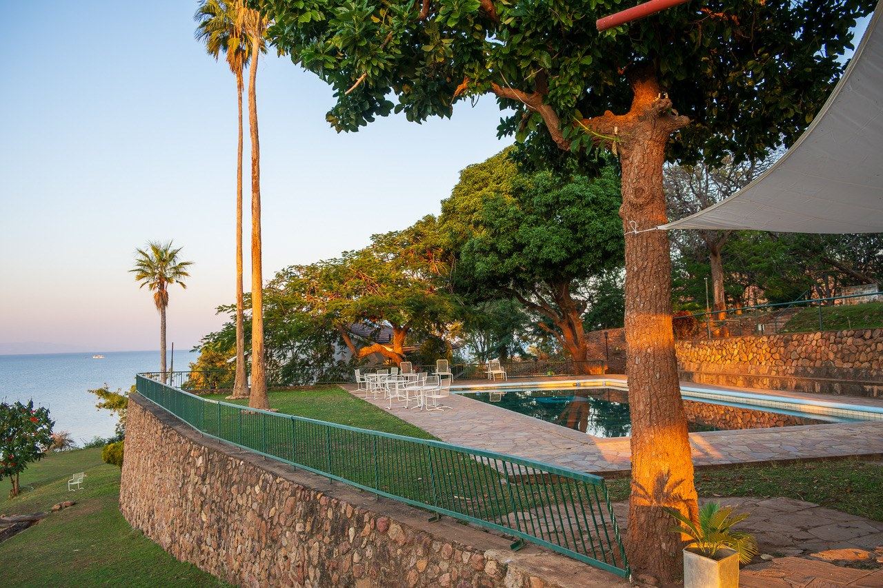 Poolside terrace with palm trees and lake views at Cutty Sark Lodge at sunset.
