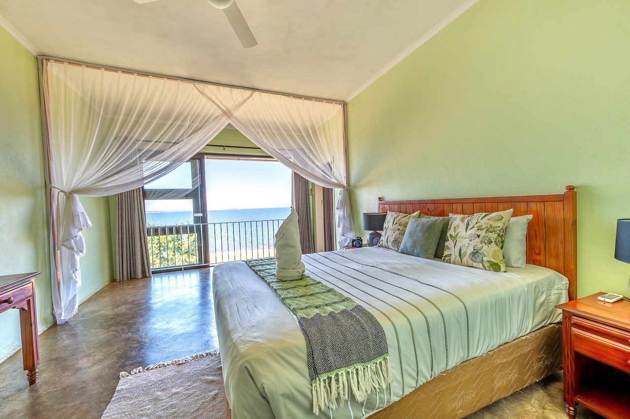 Bedroom with sheer curtains opening onto a lake-view balcony at Cutty Sark Lodge.