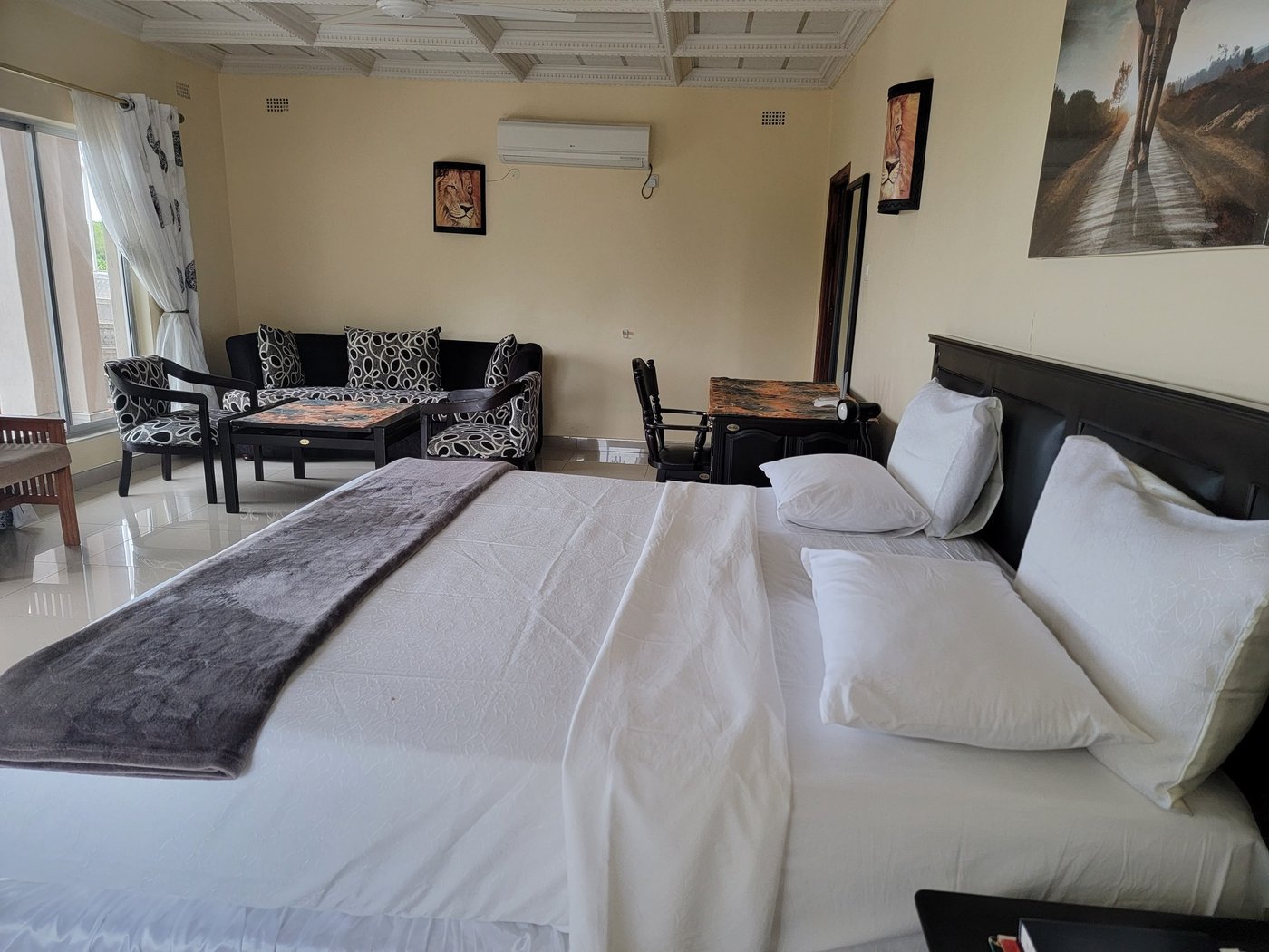 Twin beds and lounge seating fill a guest room at Dzimbabwe Lodge.