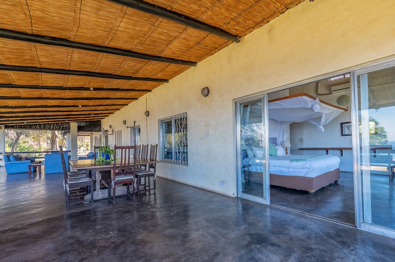 Covered veranda with dining table and bedroom suite at Fisherman's Cove, Matusadona.
