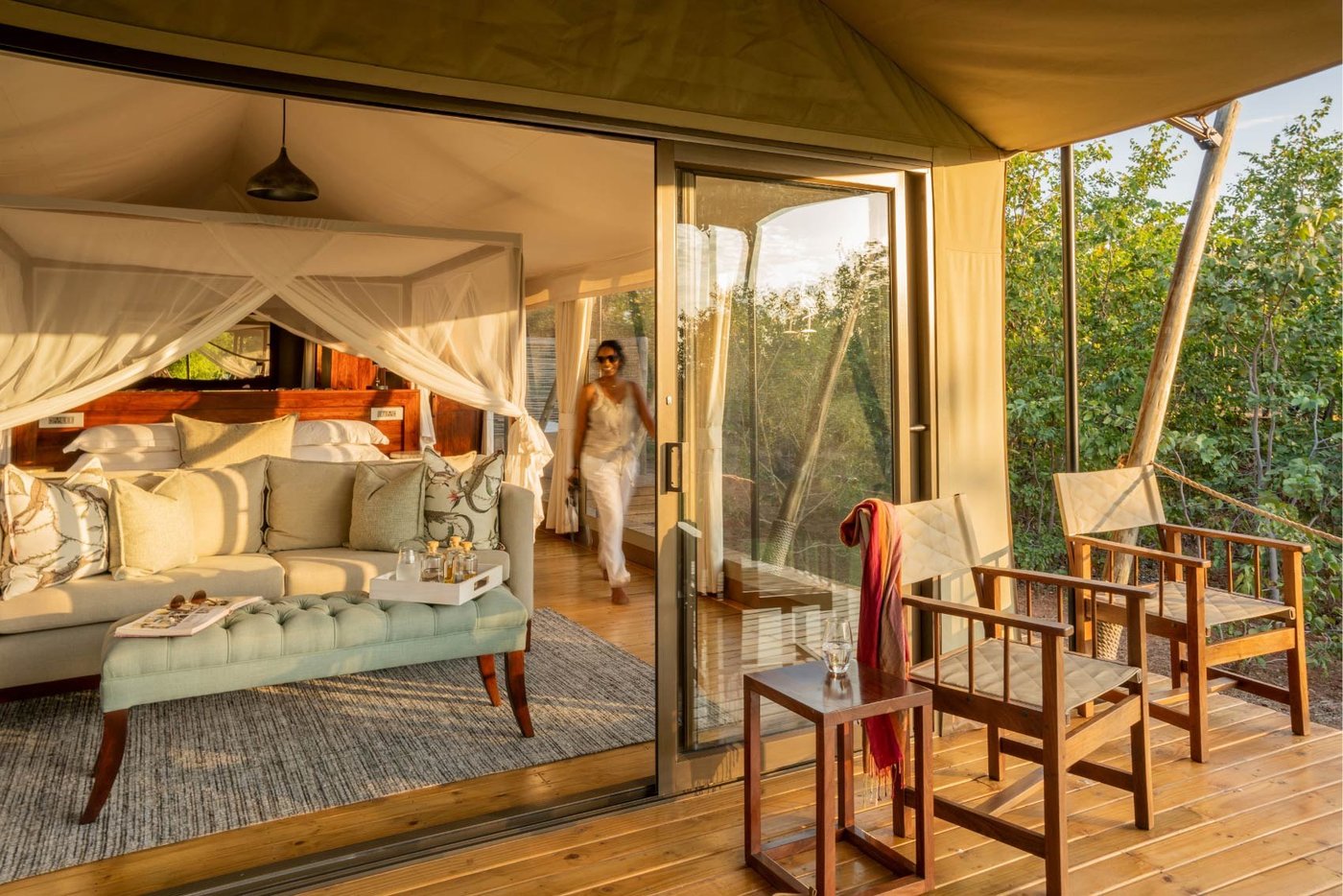 Canopied bed and lounge seating open onto a wooden deck at Fothergill's lake suite.