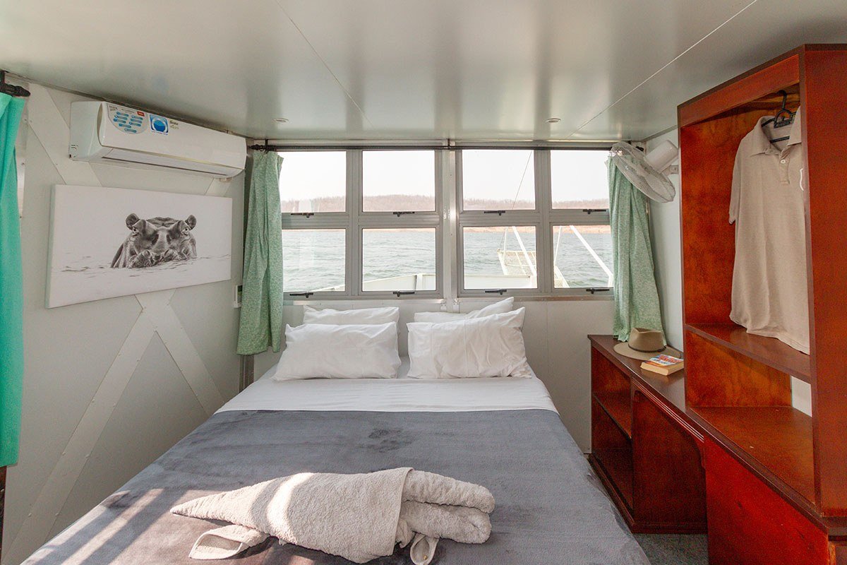 A wardrobe with sun hat and robe beside the bed in a Malachite cabin.