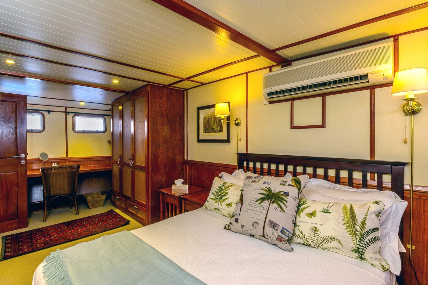 Wood-panelled cabin with portholes and a vanity desk aboard MV Matusadona.