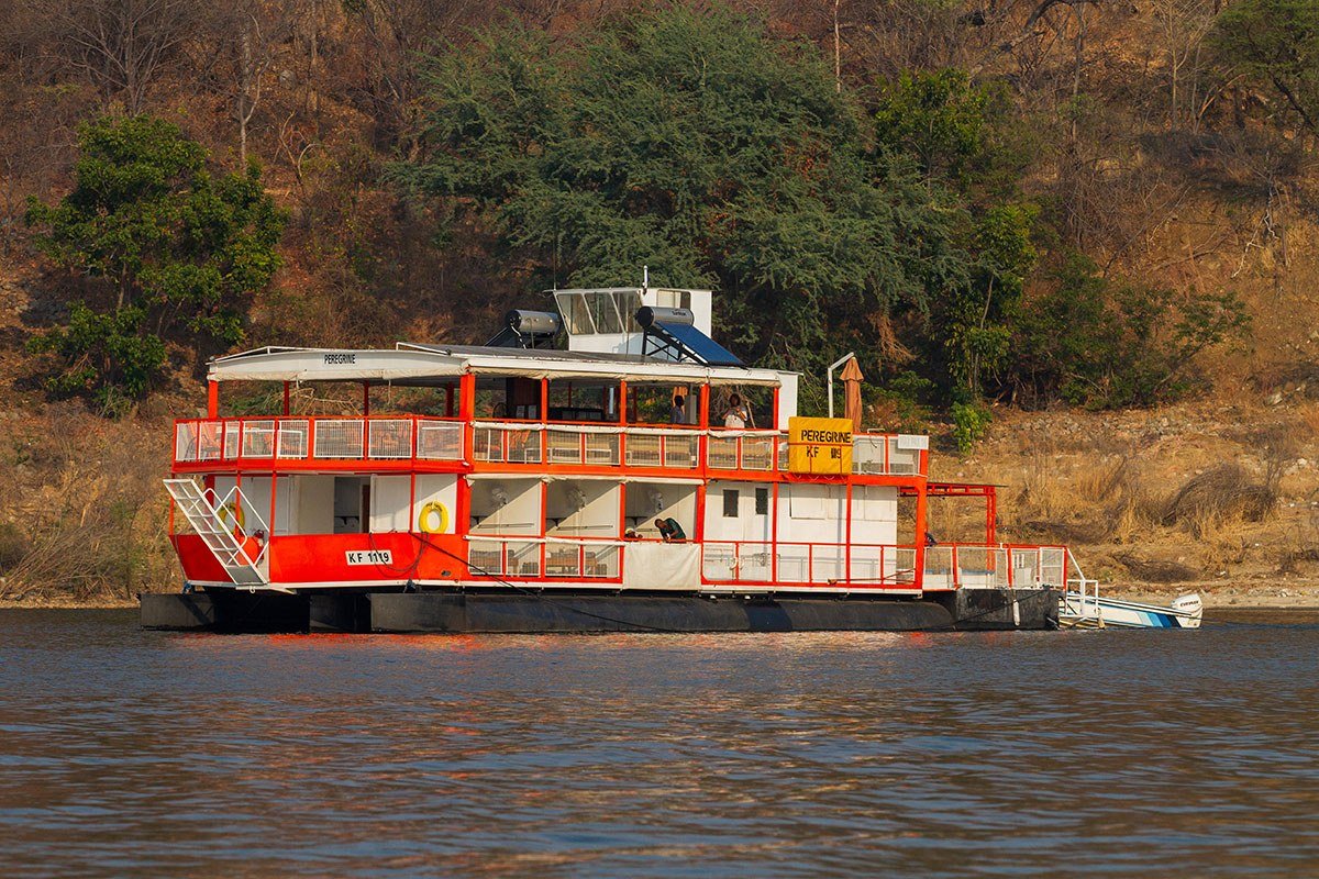 The houseboat Peregrine moored along a wooded shoreline on Lake Kariba, Matusadona.