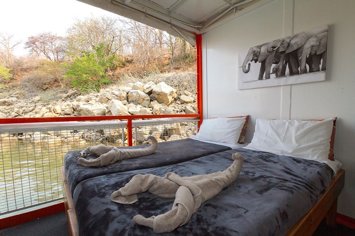 Cabin with twin beds and a rocky shoreline view aboard the Peregrine houseboat.